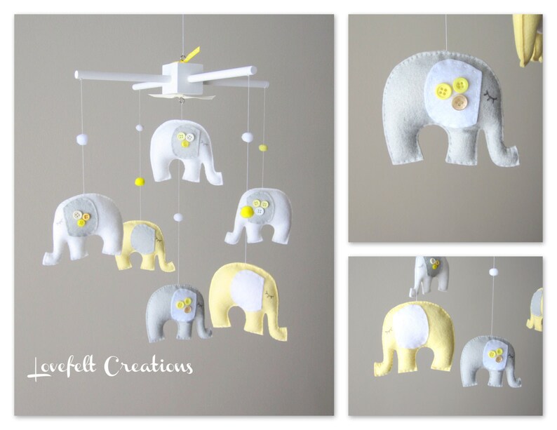 May include: A baby mobile with six grey and yellow felt elephants hanging from a white wooden frame. The elephants have white button eyes and yellow button accents.