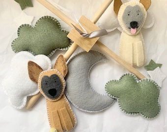 May include: A wooden baby mobile with felt clouds, a crescent moon, and two brown and white dog figures.