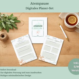 Op de afbeelding: Een digitale planner set met de tekst "Atempause" en "Digitales Planer-Set". De set bevat afdrukbare pagina's, een kopje thee met citroen en een pen op een houten oppervlak. Het ontwerp is minimalistisch.