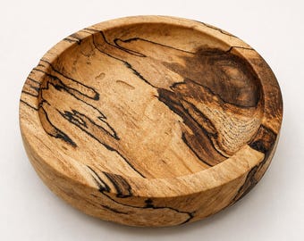 Op de afbeelding: Een ronde houten kom met een lichtbruine basiskleur en opvallende donkerbruine en zwarte spalted houtnerven over het gehele oppervlak. De kom heeft een gladde, ondiepe binnenkant en een dikke, afgeronde rand met een natuurlijke houttextuur.