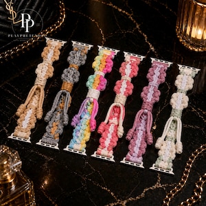 Pode incluir: Uma coleção de pulseiras de relógio de macramé em várias cores, incluindo bege, cinza, arco-íris, rosa, roxo e verde. Cada pulseira apresenta um design tecido único e conectores prateados. Exibidas em uma superfície preta com efeito mármore.