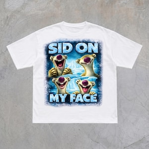Könnte beinhalten: Ein weißes T-Shirt mit kurzen Ärmeln und einem Grafikdruck von vier Sid-dem-Faultier-Figuren aus Ice Age vor einem blauen, eisigen Hintergrund. Der Text SID ON MY FACE ist in großen blauen Buchstaben über und unter den Faultier-Abbildungen gedruckt.