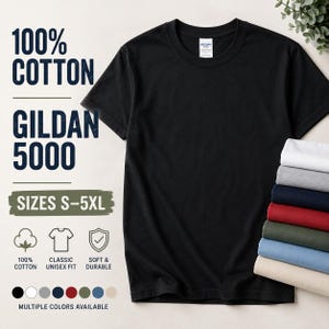 Può includere: Una t-shirt nera Gildan 5000 in 100% cotone con una classica vestibilità unisex. Il testo recita 100% COTTON, GILDAN 5000, SIZES S-5XL, 100% COTTON, CLASSIC UNISEX FIT, SOFT & DURABLE e MULTIPLE COLORS AVAILABLE. Una pila di t-shirt piegate.