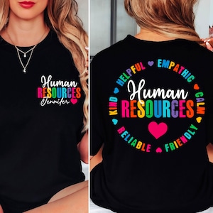 May include: Black t-shirt with the words "Human Resources" in colorful text, with the name "Jennifer" below. The back of the shirt has a circular design with the words "Helpful, Empathetic, Calm, Friendly, Reliable, Kind" around the words "Human Resources".