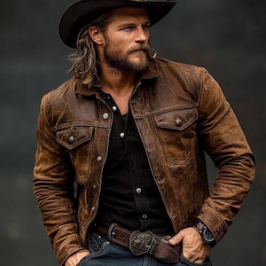 May include: A brown leather jacket with two chest pockets and button closures. The jacket is worn over a black shirt and paired with a brown belt with a decorative buckle. A cowboy hat completes the look.