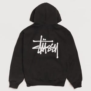 Op de afbeelding: Zwarte hoodie met een wit logo op de achterkant. Het logo is een gestileerd scriptontwerp. De hoodie heeft een capuchon en lange mouwen. De stof lijkt een zacht, comfortabel materiaal te zijn.