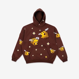 May include: A dark brown hooded sweatshirt featuring a repeating pattern of yellow and black pixelated bees with white wings. The design includes small white pixelated flower icons scattered across the fabric and a front kangaroo pocket.