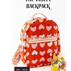 May include: A quilted backpack in burnt orange featuring a repeating pattern of light pink strawberries. The bag has a top handle, a front zippered pocket, and the text THE VIOLET BACKPACK and KNOT + THREAD DESIGN printed on the image.