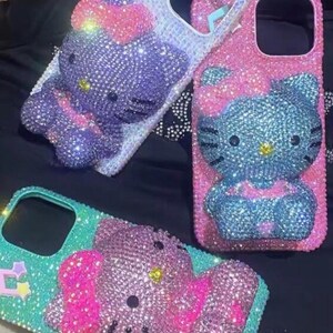 Puede incluir: Tres fundas de tel&eacute;fono adornadas con pedrer&iacute;a con un dise&ntilde;o de Hello Kitty. Las fundas son en tonos rosa, azul, morado y turquesa, con brillantes pedrer&iacute;a. Las fundas tienen recortes para la c&aacute;mara y los botones.