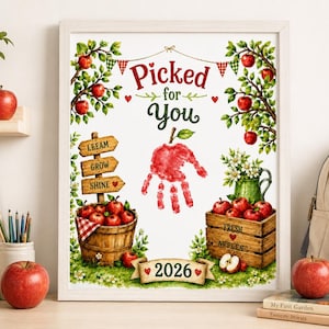 Puede incluir: Una lámina enmarcada con ilustraciones en acuarela de manzanos, un letrero de madera que dice "LEEARN GROW SHINE", una cesta y una caja de manzanas rojas, y una huella de mano roja con forma de manzana con el texto "Picked for You 2026".