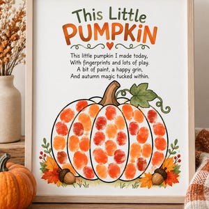 May include: A framed print featuring the text This Little Pumpkin and a poem about fingerprints. The center shows a large pumpkin outline filled with orange and red fingerprint art, accented by autumn leaves and two acorns at the base.