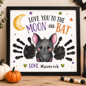 May include: A framed print featuring a cartoon bat with pink ears and two black handprint wings. The text reads LOVE YOU TO THE MOON AND BAT and LOVE, Maverick. The design includes a yellow crescent moon, colorful stars, and green hearts.
