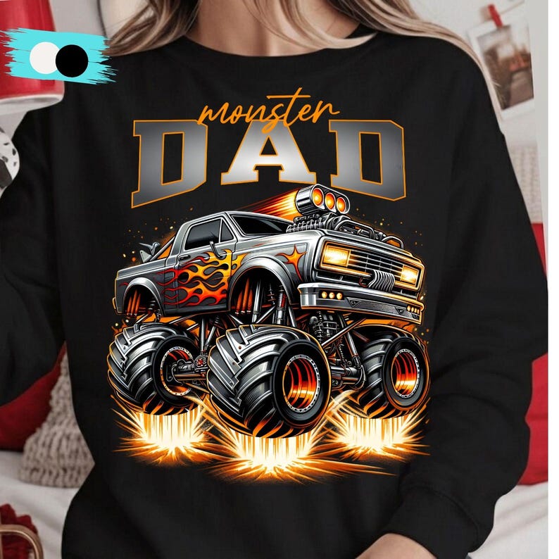 Pode incluir: Camisola preta com um design de monster truck com chamas e o texto "monster DAD" em laranja e cinza. O caminh&atilde;o tem pneus grandes e emite fa&iacute;scas, criando um design din&acirc;mico.