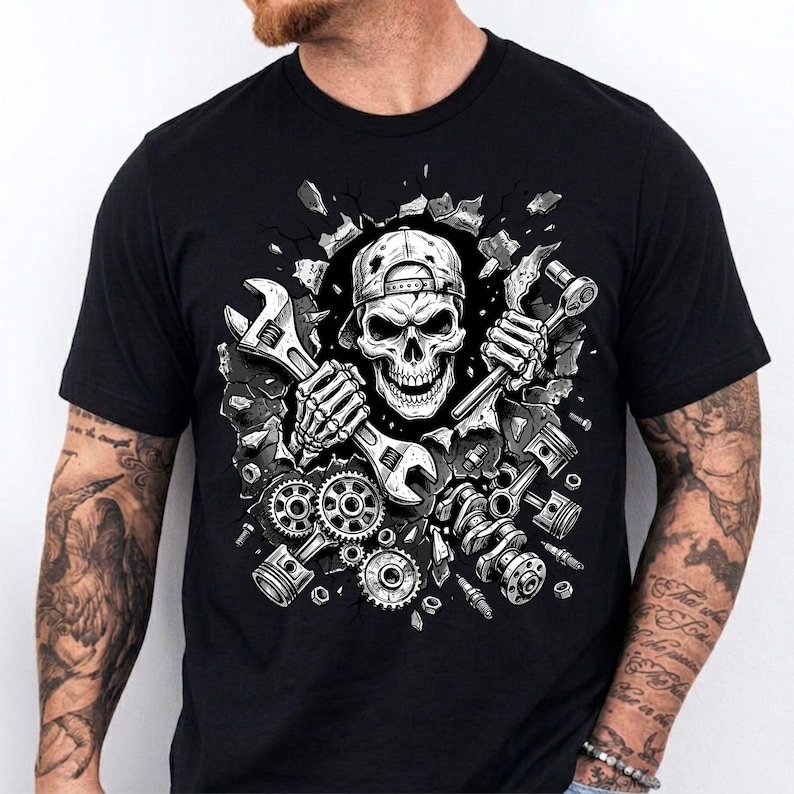 May include: Black t-shirt featuring a detailed graphic of a skull wearing a backwards baseball cap, holding wrenches and surrounded by engine parts. The design has a mechanic theme, with gears, pistons, and other tools.