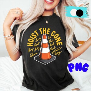 May include: Black t-shirt with the phrase "HOIST THE CONE" in yellow and a graphic of an orange and white traffic cone. The shirt also features several names in a handwritten style around the cone.