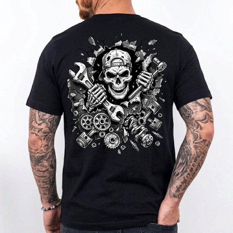 May include: Black t-shirt featuring a detailed graphic of a skull wearing a cap, holding wrenches, and surrounded by engine parts. The design is in shades of gray and white, with a cracked wall effect. A unique design for mechanics and car enthusiasts.