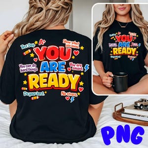 Puede incluir: Camiseta negra con la frase "YOU ARE READY" en rojo, azul y amarillo, con texto y gráficos adicionales. El diseño incluye estrellas, corazones y lápices. Corte casual, adecuado para el uso diario.