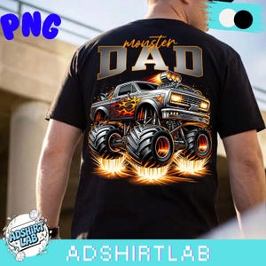 Pode incluir: Camiseta preta com um gr&aacute;fico de monster truck e o texto "monster DAD". O caminh&atilde;o &eacute; prateado e laranja, com chamas e pneus grandes. O design da camiseta &eacute; da ADSHIRTLAB.