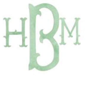 Può includere: Un monogramma verde chiaro con le lettere H, B e M in un carattere serif decorativo. Le lettere sono disposte con la B al centro, leggermente più grande della H a sinistra e della M a destra. Lo sfondo è bianco.