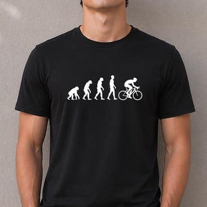 Può includere: Una t-shirt nera a maniche corte con una stampa grafica bianca che raffigura l'evoluzione dell'umanità, partendo da un primate e progredendo attraverso varie fasi fino a una figura umana in sella a una bicicletta.
