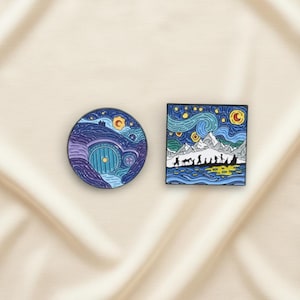 Può includere: Due spille smaltate. Una è un design circolare di un buco di hobbit con un cielo stellato blu e viola. L'altra è una spilla quadrata con un design a notte stellata e una silhouette di un gruppo di persone che camminano.