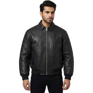 May include: A black leather bomber jacket featuring a subtle embossed spiderweb pattern across the chest and sleeves. The jacket includes a classic collar, a full-length silver-toned metal front zipper, and ribbed cuffs and hem for a secure fit.