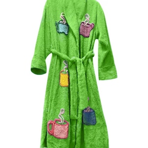 May include: A bright lime green terry cloth bathrobe featuring long sleeves, a shawl collar, and a matching tie belt. The robe is decorated with embroidered patches of colorful coffee mugs in shades of blue, pink, yellow, and purple with steam.