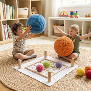 Op de afbeelding: Twee kinderen spelen met grote, gehaakte ballen in blauw en oranje. Een houten spelbord met kleurrijke gehaakte ballen in roze, groen en paars ligt op een kleed. De scène speelt zich af in een speelkamer met houten planken.