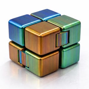 May include: A multi-colored metal fidget cube with a gradient finish. The cube is composed of eight connected blocks in shades of blue, green, and gold. The blocks are arranged in a cube shape, with each block having a smooth, metallic surface.