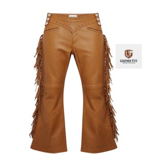 May include: Tan leather trousers with decorative stitching and fringe along the sides. The trousers have a flared leg design and button details at the waist. The Leather Fitz logo is in the upper right corner.