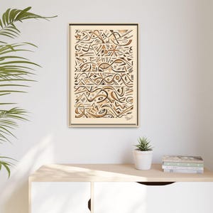 May include: Abstract art print in a beige frame. The artwork features a series of geometric shapes and lines in shades of brown and black, creating a layered and textured effect. The print is displayed on a white wall above a wooden cabinet.