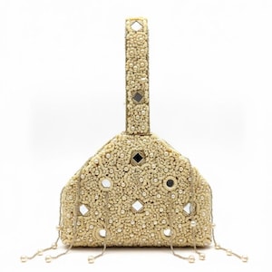 Può includere: Borsa a mano color avorio con perline e manico. La borsa è decorata con piccole perle, specchi e elementi decorativi. Fili di perle pendono dal basso. Il manico è anch'esso decorato con perline e specchi. La borsa ha una forma triangolare.