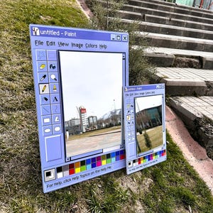 Puede incluir: Dos espejos enmarcados en azul dise&ntilde;ados como la interfaz cl&aacute;sica del programa Windows Paint. El espejo m&aacute;s grande muestra un paisaje urbano, mientras que el m&aacute;s peque&ntilde;o refleja una vista diferente. El texto "untitled - Paint" y las opciones del men&uacute; son visibles.