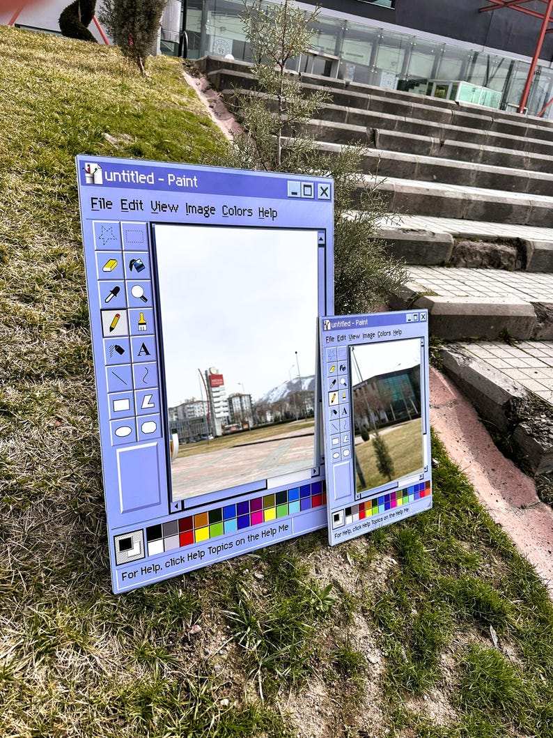 Puede incluir: Dos espejos enmarcados en azul dise&ntilde;ados como la interfaz cl&aacute;sica del programa Windows Paint. El espejo m&aacute;s grande muestra un paisaje urbano, mientras que el m&aacute;s peque&ntilde;o refleja una vista diferente. El texto "untitled - Paint" y las opciones del men&uacute; son visibles.