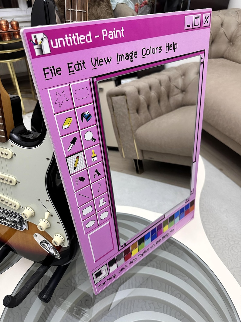 May include: A pink framed mirror designed to resemble the classic "Untitled - Paint" application window. The mirror features a color palette and menu options like "File Edit View Image Colors Help". A guitar is visible in the background.