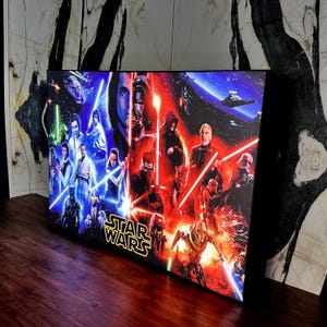 Könnte beinhalten: Ein rechteckiger Star Wars-Leinwanddruck mit Charakteren aus der Filmreihe. Das Kunstwerk ist in blaue und rote Hälften unterteilt und zeigt Helden und Schurken mit Lichtschwertern. Das Star Wars-Logo befindet sich unten.
