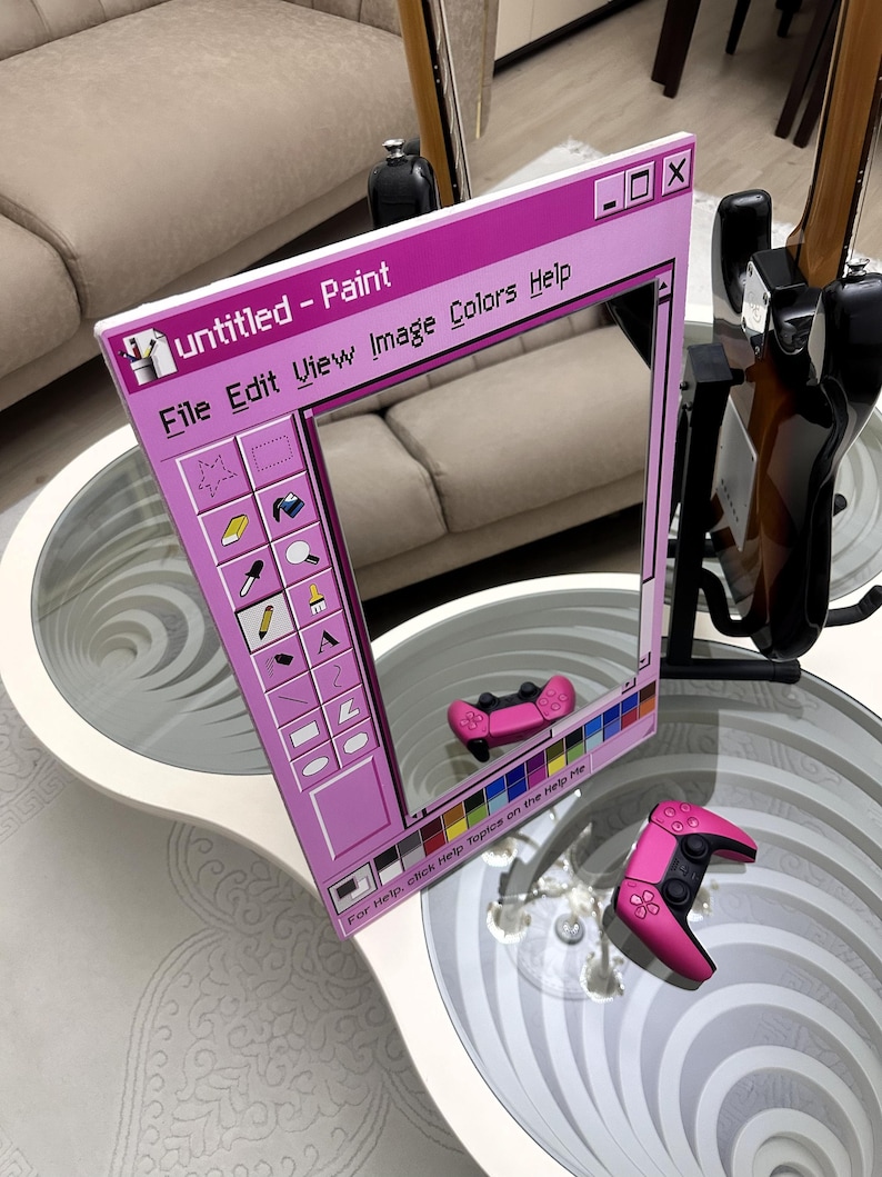 May include: A pink mirror in the shape of a computer window, with the text "Untitled - Paint" at the top. The mirror reflects a pink game controller. The window design includes a toolbar with icons and the text "File Edit View Image Colors Help".