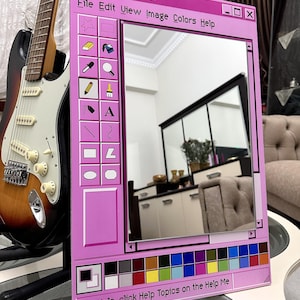 May include: A pink mirror designed to look like a classic computer Paint window. The mirror has a frame with a colour palette, icons, and the text "untitled - Paint". A guitar is visible in the background.
