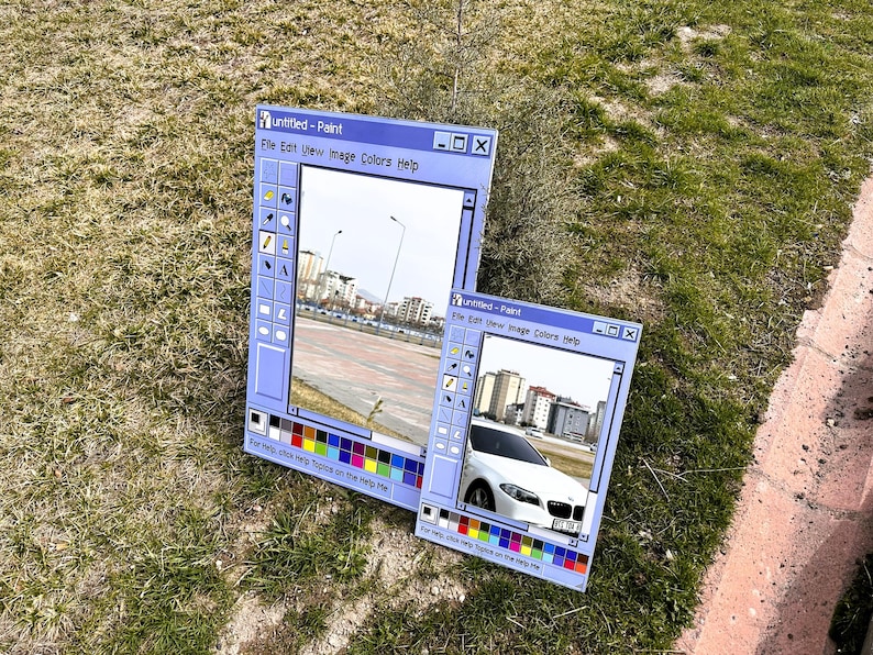 Puede incluir: Dos obras de arte de tem&aacute;tica azul que se asemejan a la interfaz del programa Windows Paint cl&aacute;sico. La m&aacute;s grande muestra un paisaje urbano, la m&aacute;s peque&ntilde;a un coche blanco. Ambas est&aacute;n sobre hierba.