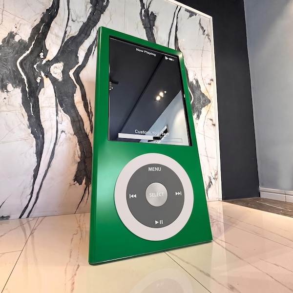 May include: A large, green, rectangular media player display featuring a circular control interface with a central Select button, Menu text, and playback icons. The screen displays the text Now Playing and Custom Your Text in white font.