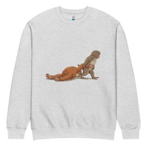Könnte beinhalten: Hellgraues Sweatshirt mit einer humorvollen Illustration von zwei Affen. Einer zieht den anderen, der auf dem Boden liegt. Das Design verwendet Braun- und Grautöne und erzeugt eine spielerische und auffällige Grafik.