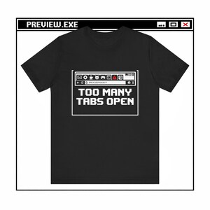May include: Black t-shirt with a pixelated computer window design. The text "TOO MANY TABS OPEN" is displayed in white, along with a simulated browser interface at the top. The top of the shirt reads "PREVIEW.EXE".