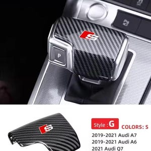 Könnte beinhalten: Schaltknaufabdeckung aus Kohlefaser mit rotem und silbernem "S"-Logo. Die Abdeckung ist für Audi A7, A6 und Q7 Modelle konzipiert. Das Bild zeigt auch eine passende Abdeckung und den Innenraum des Autos.