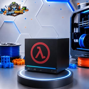 Könnte beinhalten: Ein schwarzes, würfelförmiges Computergehäuse mit einem roten Lambda-Symbol auf der Vorderseite. Das Gerät verfügt über einen dünnen horizontalen Lichtstreifen, zwei USB-Anschlüsse und einen Ein-/Ausschalter. Das Logo LayerNerds ist oben links zu sehen.