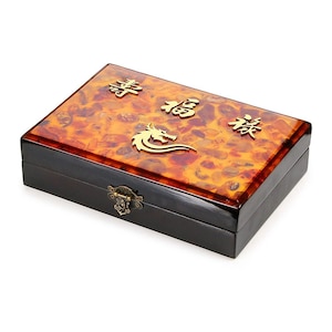May include: Rectangular wooden box with a glossy finish. The lid features a mottled orange and brown pattern, gold Chinese characters, and a dragon emblem. The box has a dark brown base and a decorative clasp.