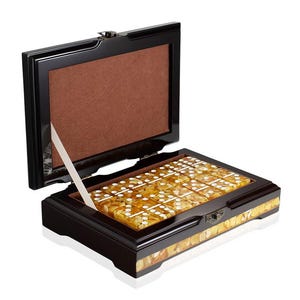 May include: A wooden domino set in a black lacquered box with a hinged lid. The dominoes are amber-colored with white dots. The box has a brown interior and a decorative border.