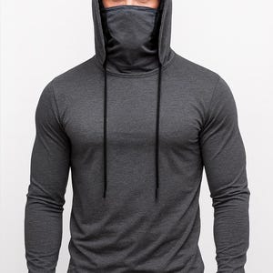 May include: A dark gray long-sleeved hoodie with a built-in face covering. The hood has drawstrings, and the fabric appears to be a soft, comfortable material. The design is simple and practical, suitable for various activities.