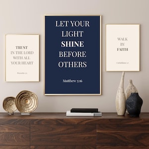 Könnte beinhalten: Drei gerahmte Drucke mit inspirierenden Zitaten. Der zentrale Druck trägt den Text "LET YOUR LIGHT SHINE BEFORE OTHERS" auf marineblauem Hintergrund. Die anderen beiden Drucke tragen die Texte "TRUST IN THE LORD WITH ALL YOUR HEART" und "WALK BY FAITH".