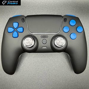 May include: Black games controller with blue buttons and accents. The controller features two analogue sticks, a directional pad, and several buttons. The brand name "Control Freakz" is visible in the upper left corner.