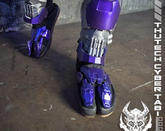 May include: Purple and gray cybernetic leg armor. The armor is a combination of metallic gray and glossy purple, with intricate mechanical details. The text "PURPLE THUTECH CYBERTABI" is visible. The logo for "TWOHORNSUNITED CREATIONS" is also visible.